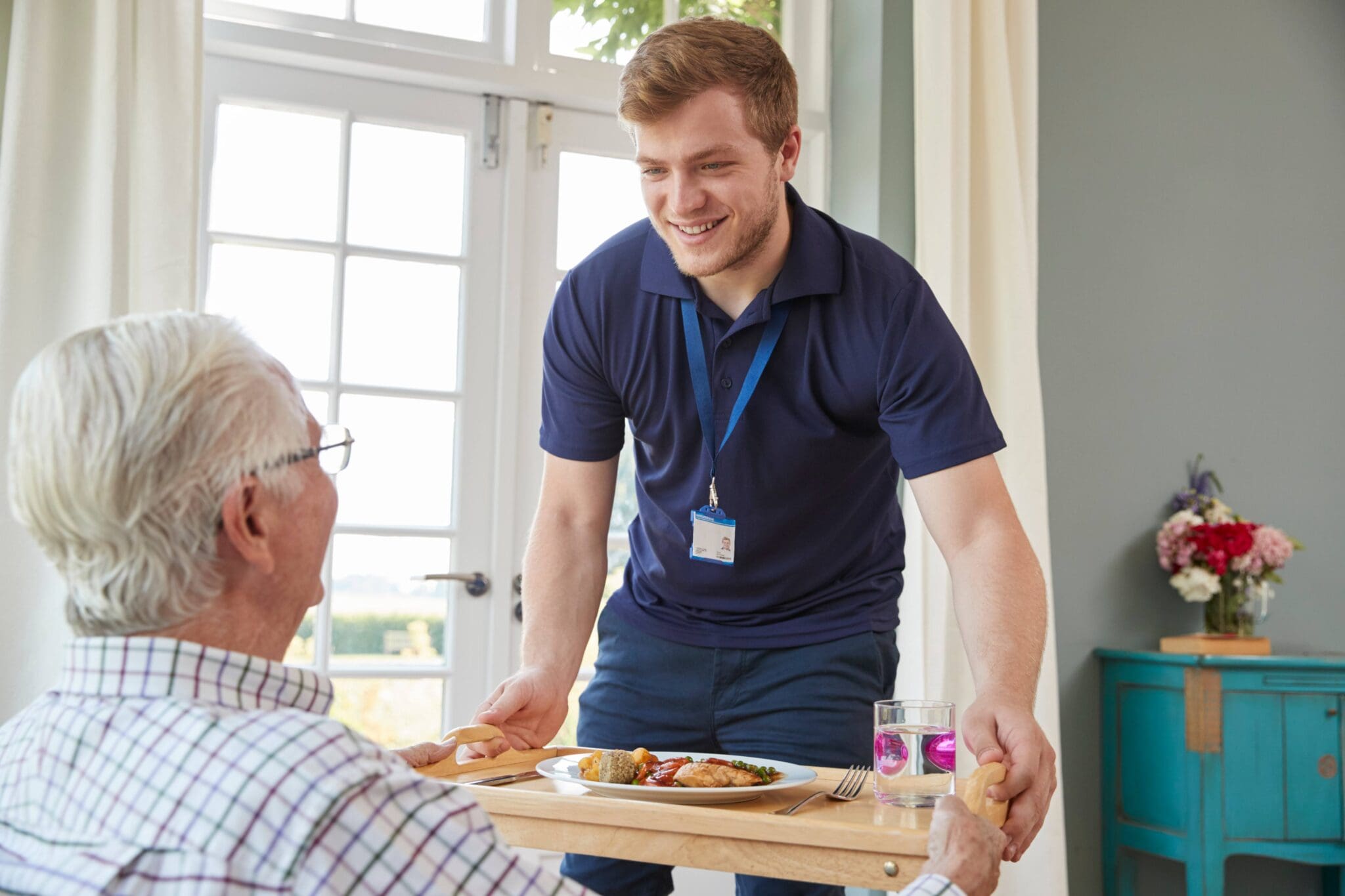 Caregiver serving senior a meal.
