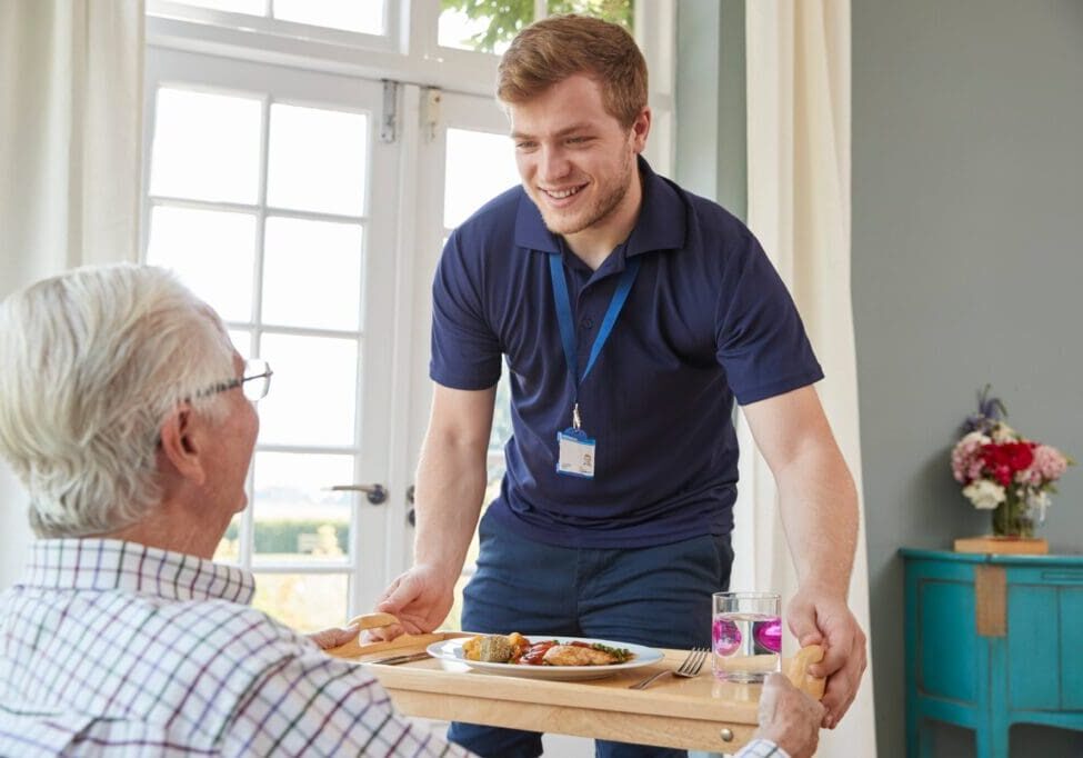 Caregiver serving senior a meal.